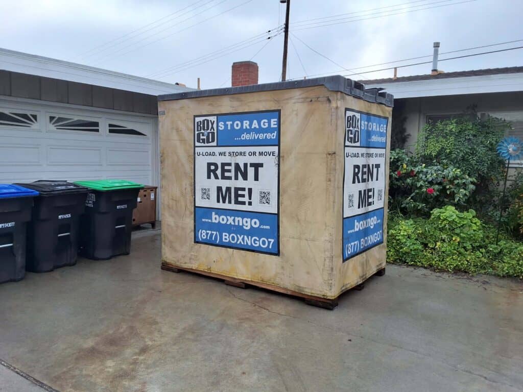 Box-n-Go storage container placed on a driveway beside trash bins in a residential area of Jefferson Park.
