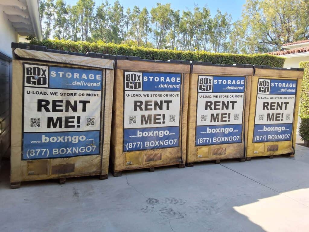 Four Box-n-Go storage containers labeled "RENT ME!" placed on a driveway in a sunny Encino residential area.