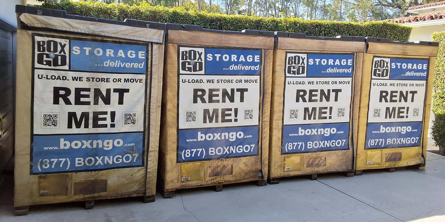 Four Box-n-Go storage containers labeled "RENT ME!" placed on a driveway in a sunny Encino residential area.