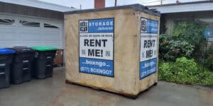 Box-n-Go storage container placed on a driveway beside trash bins in a residential area of Jefferson Park.