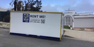 Box-n-Go storage container placed on a residential street in Santa Monica, near a white house with a decorative arched gate.