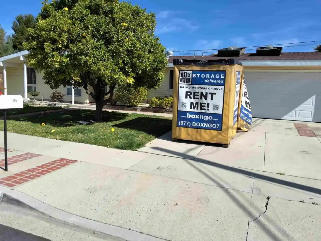 A Box-n-Go portable storage container sits in a residential driveway, offering convenient door-to-door Self Storage in Century City CA under a bright blue sky
