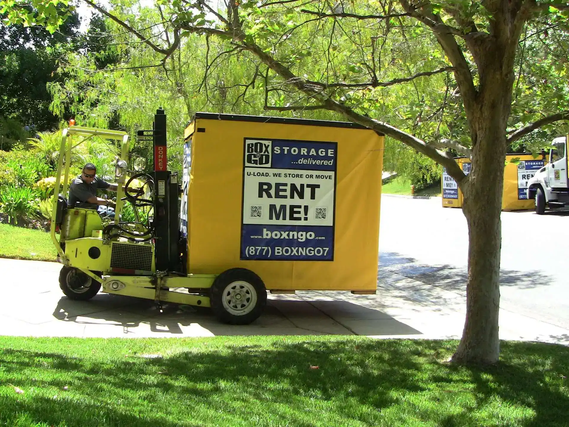 Box-n-Go portable moving containers being delivered to a residential neighborhood by forklift, ideal for convenient and secure DIY moves or temporary storage during relocation.