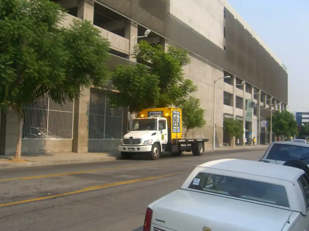 Box-n-Go storage container being delivered by truck in an urban area near Paramount, CA, highlighting convenient and mobile self storage in Paramount CA for businesses and residents.