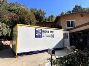 Large Boxngo storage container placed in front of a house, offering convenient temporary storage solutions. Perfect for organizing belongings during moving, home renovation, or decluttering. The container is easily accessible for loading and unloading.