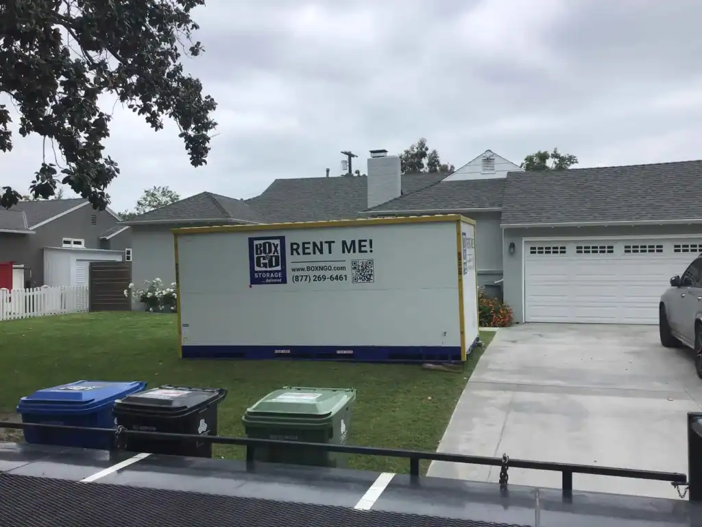 Moving Boxes Delivery in West Hollywood CA - A portable storage container from Box-N-Go Storage is parked on a residential lawn, ready for moving or storage needs.