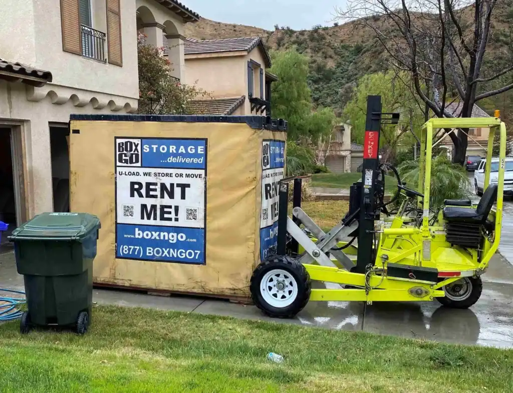 Portable Box-n-Go storage container being delivered to a residential home in rainy weather, showcasing flexible self storage in Downey CA for moving and temporary storage needs.