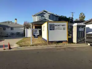 Residential construction site in Santa Monica with a Box-n-Go portable unit used for office inventory storage, featuring a contractor sign and portable restroom on the front lawn.
