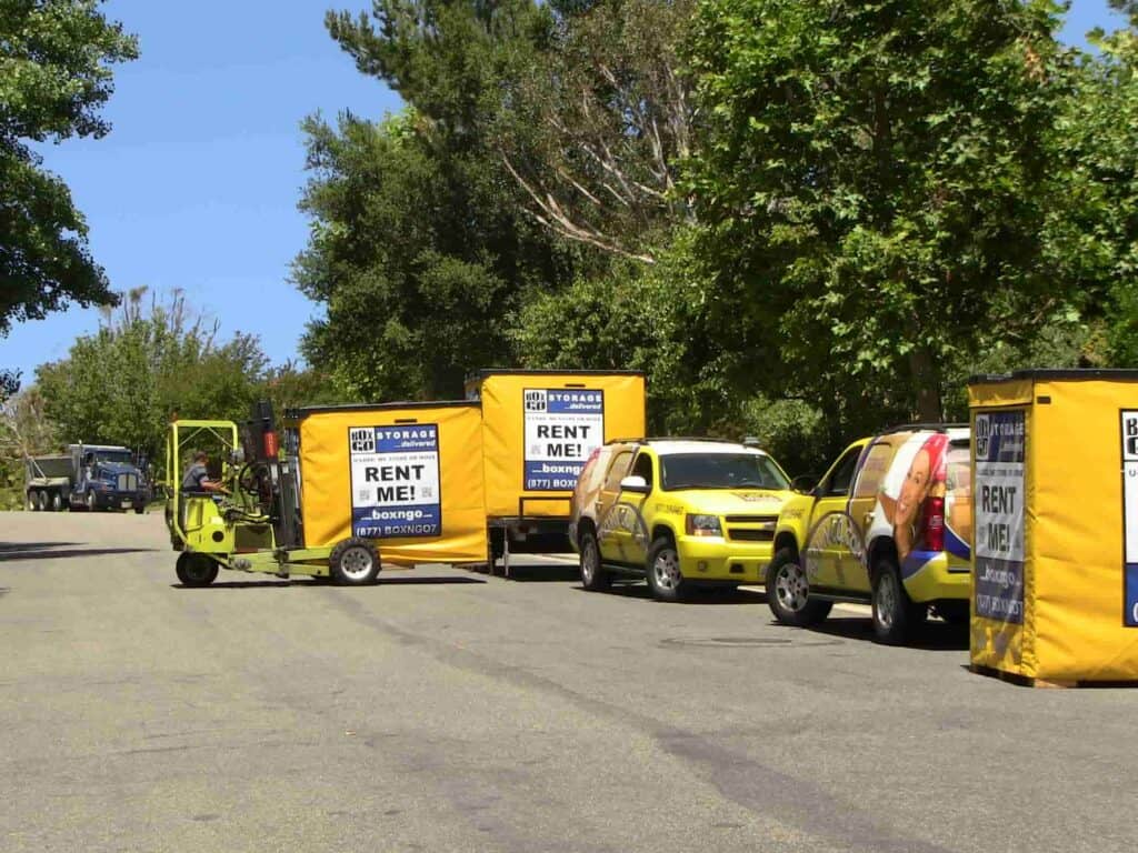 Box-N-Go portable self storage Venice containers beside branded trucks.