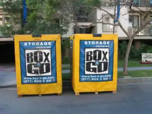 Bright yellow Box-n-Go portable containers placed outside luxury apartments for convenient short term storage in Sherman Oaks, ideal for residential moves or temporary space solutions.