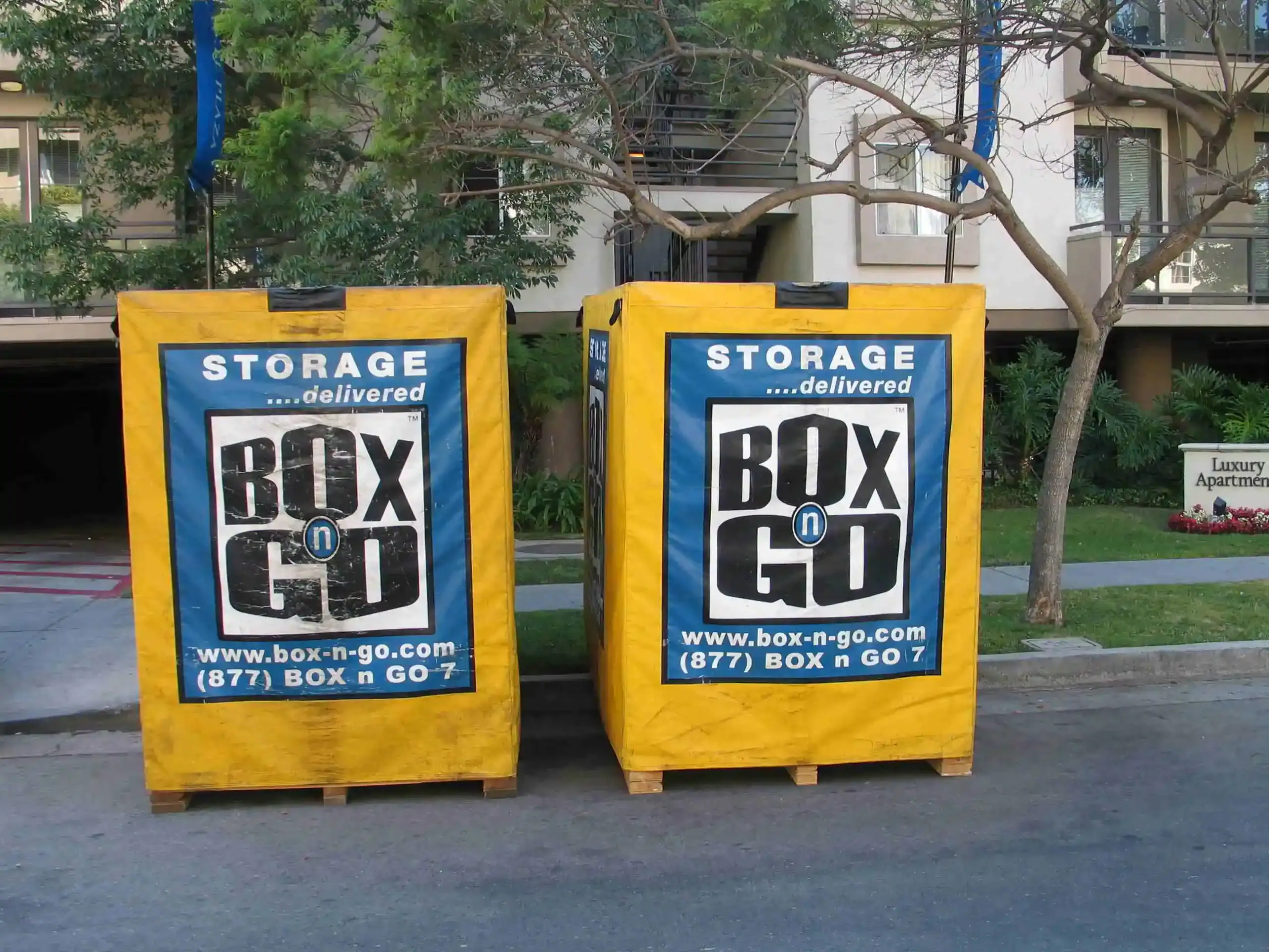 Bright yellow Box-n-Go portable containers placed outside luxury apartments for convenient short term storage in Sherman Oaks, ideal for residential moves or temporary space solutions.
