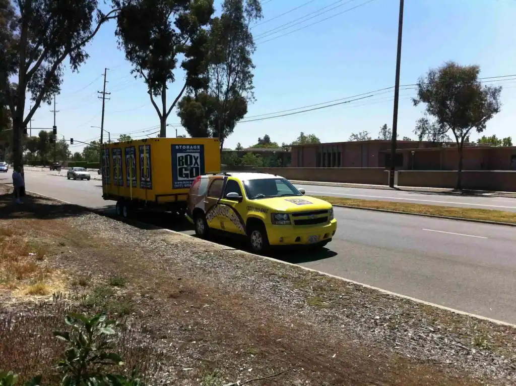 Bright yellow Box-n-Go truck and trailer parked on a street, representing professional moving and storage services in Sherman Oaks, ideal for residential or commercial relocations.