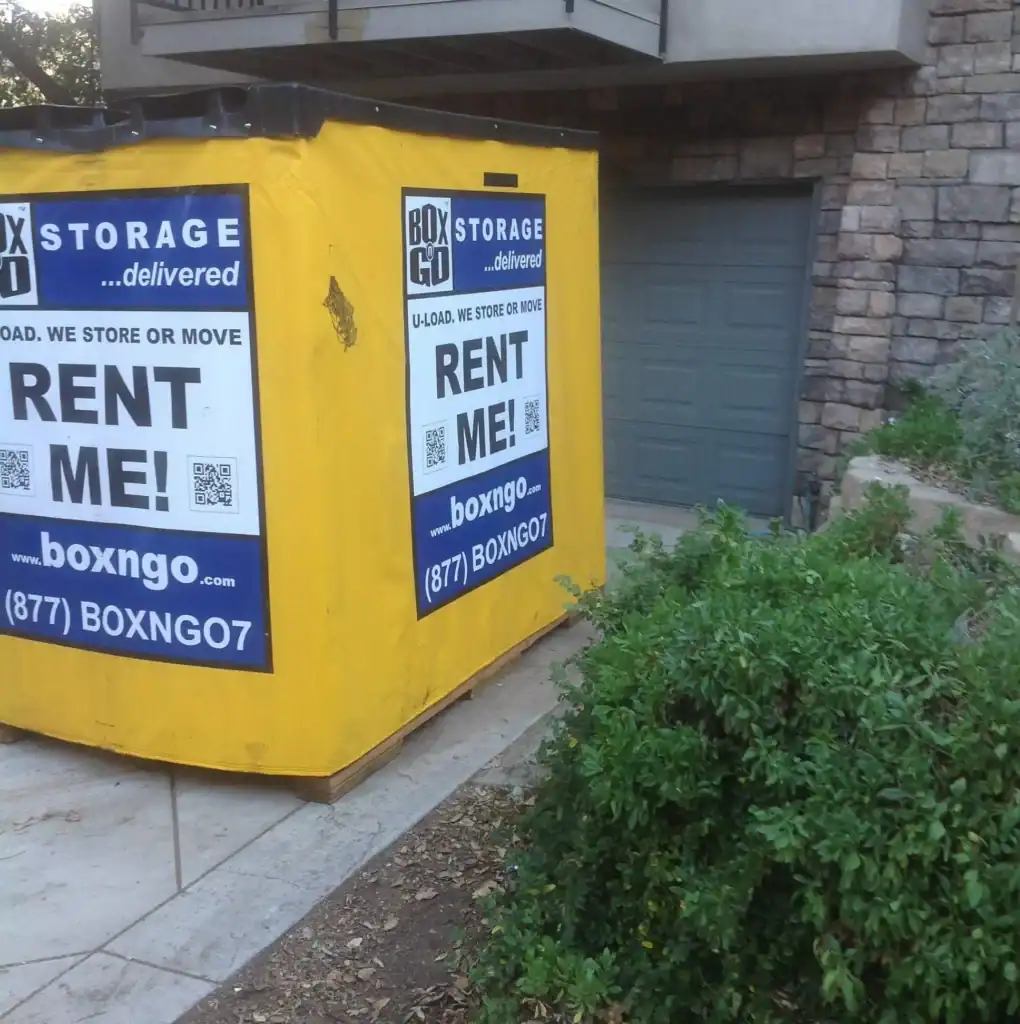 Bright yellow portable storage container from Box-n-Go placed in front of a residential garage, promoting convenient and flexible self storage in Arleta CA for moving or temporary storage needs.