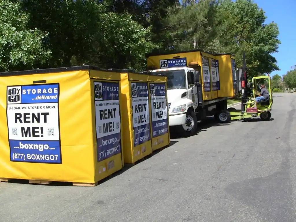 Delivery of portable self storage units in Canyon Country CA by Box-n-Go, with yellow storage containers being unloaded from a truck using a forklift on a suburban street.
