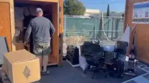 Man organizing portable storage unit with furniture and boxes, showcasing downsizing tips for seniors Encino to simplify moving and save space.