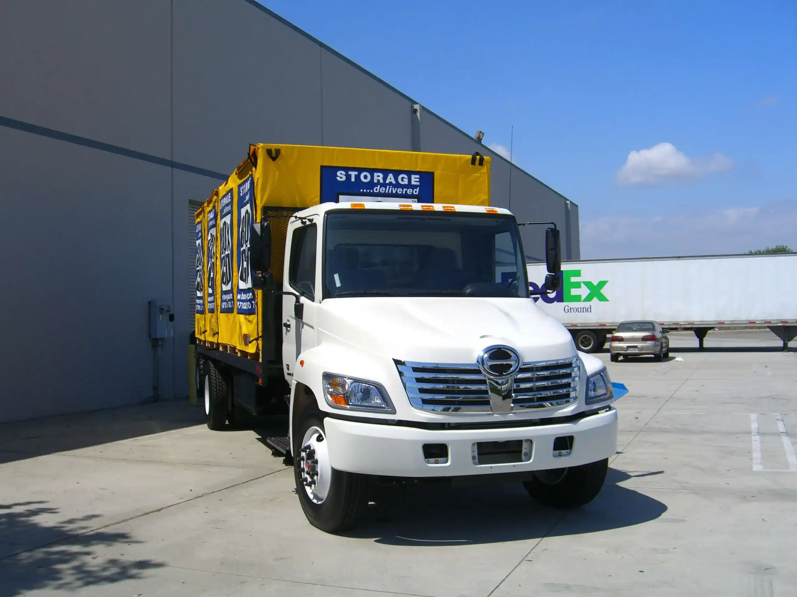 Professional moving and storage services in Encino – branded delivery truck loading secure storage containers at a commercial facility, ready for local or long-distance moves.