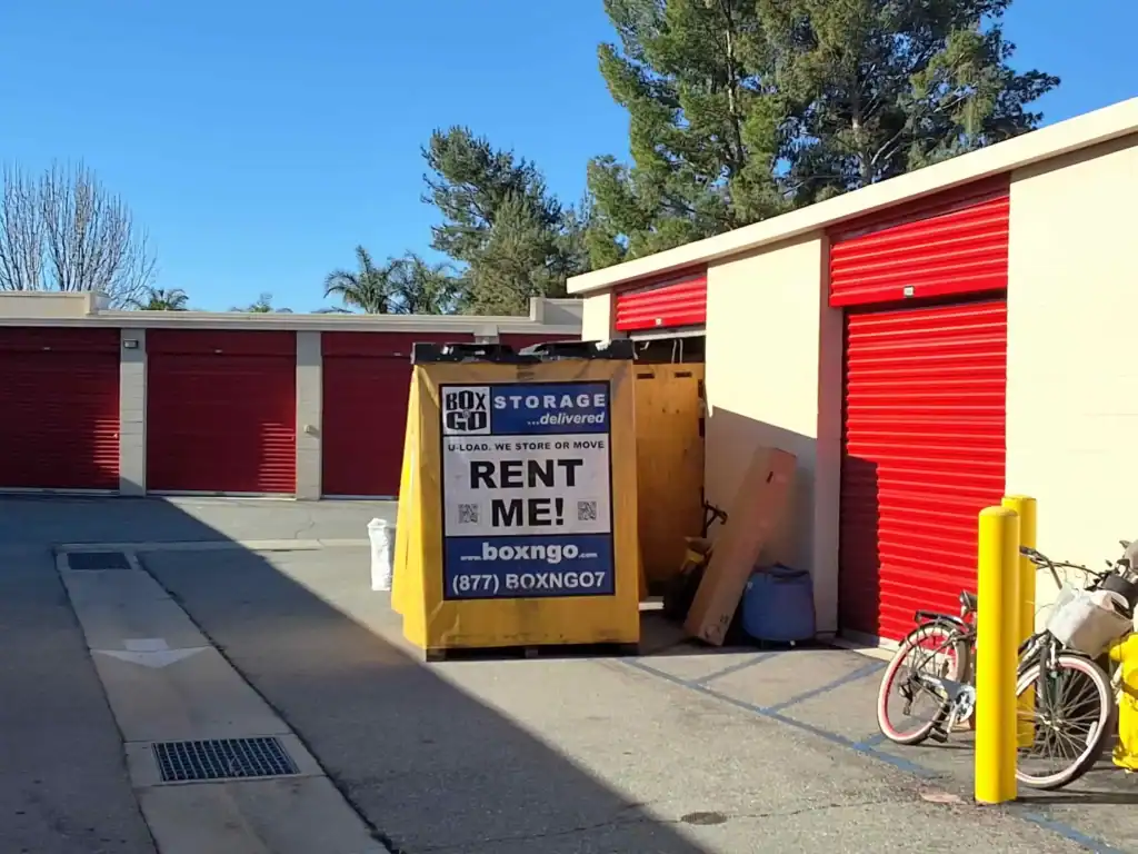 Self storage units in Canoga Park, CA, with a BoxGo storage container available for rent in front of red storage unit doors. Ideal for moving, storing, or organizing belongings in Canoga Park, CA.