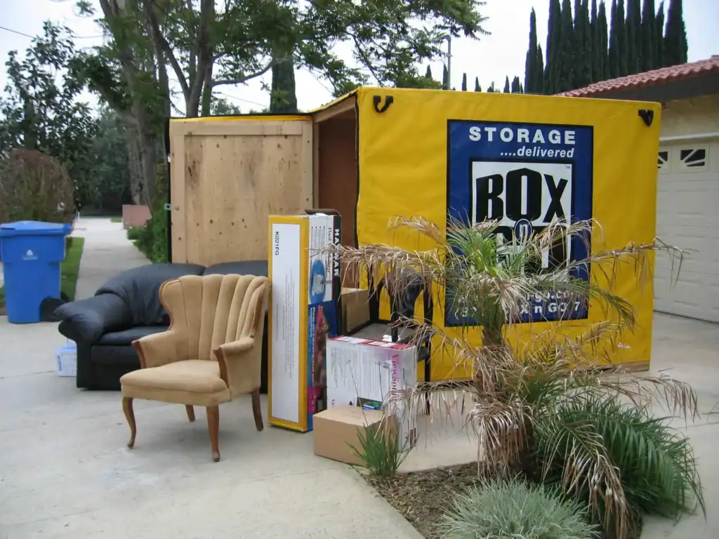 Storage after divorce – Box-n-Go portable storage container filled with household items and furniture outside a suburban home, offering a convenient solution for organizing and storing belongings during a life transition.