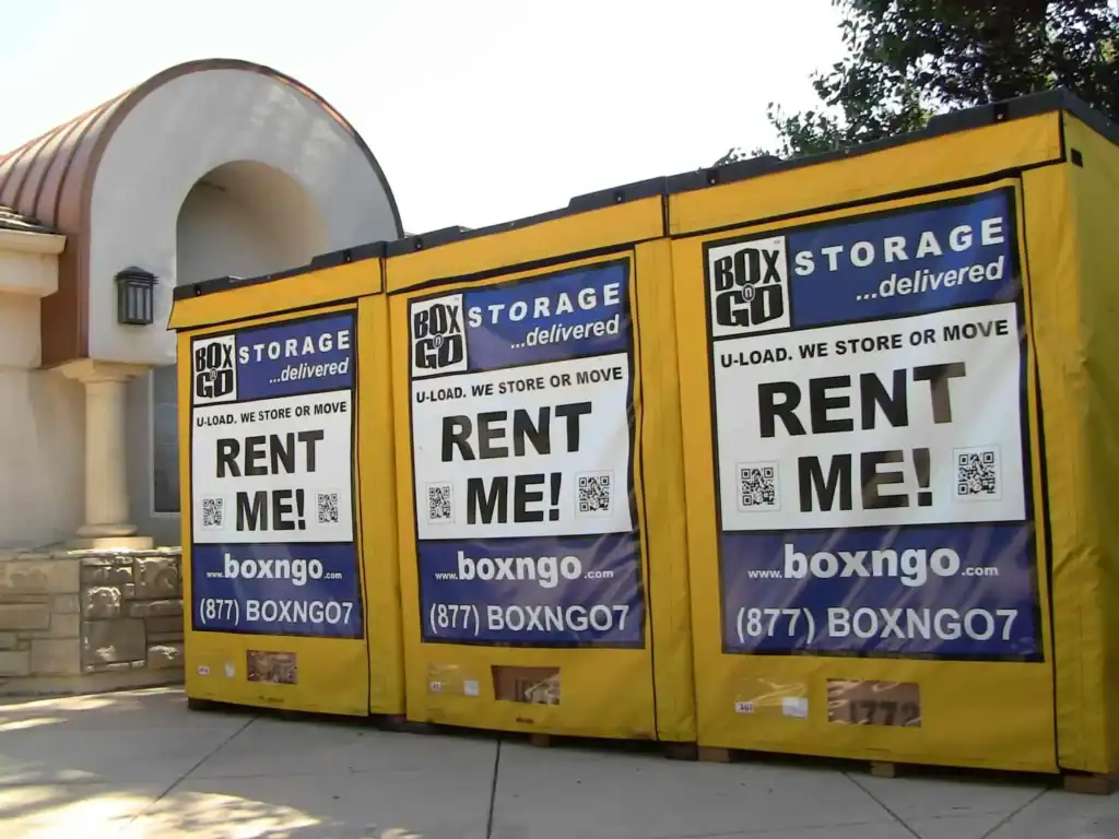 Three yellow Box-n-Go portable storage units placed outside a building, highlighting convenient portable storage Montrose solutions for moving, remodeling, and temporary on-site storage.
