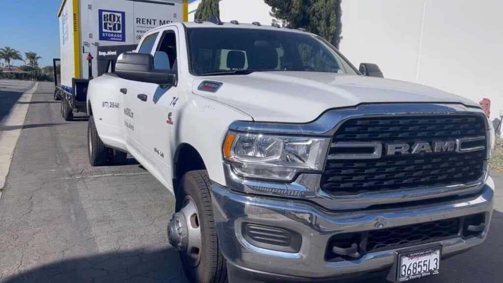 A large white RAM truck pulls a Box-n-Go portable storage container on a trailer, illustrating convenient and flexible self-storage-encino solutions for residential and commercial needs.
