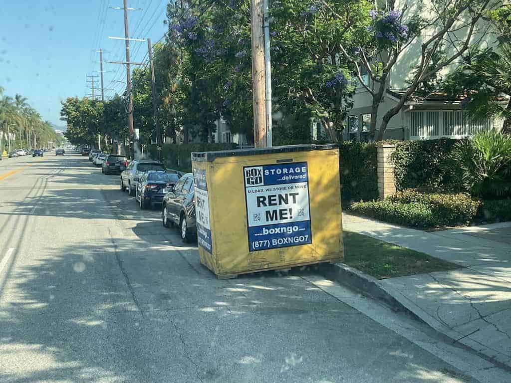A cal poly summer storage unit parked in a street with SUV visible.