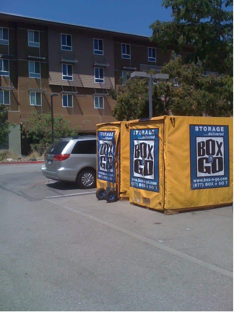 Yellow Box-n-Go csuf student storage container in a parking lot near the dolly.