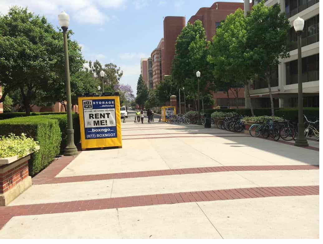 Box-n-Go storage units near usc on a campus walkway with trimmed hedges.