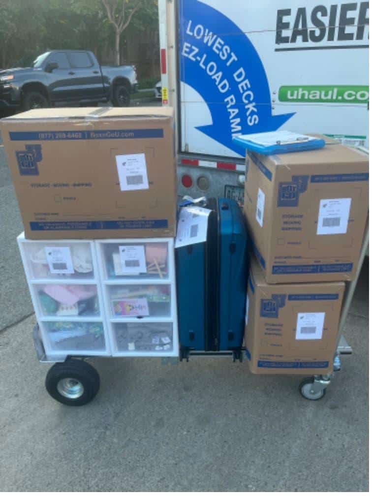 Student items including boxes and bins on a cart packed and labeled for CMC student storage.