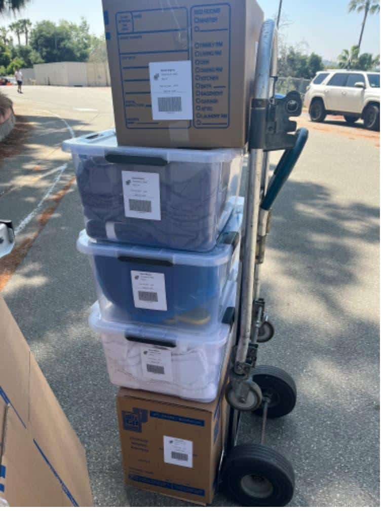 Student items including clear bins on a dolly packed and labeled for student moving and storage.