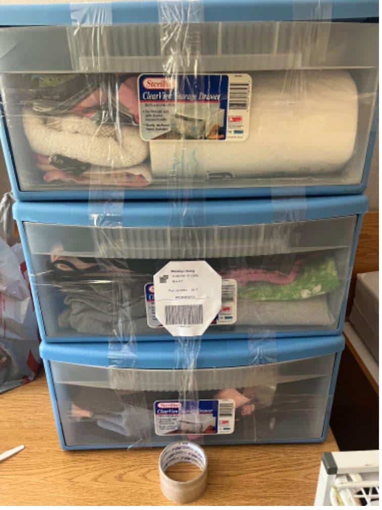Student items including blue plastic drawers packed and labeled for csuf dorm storage.