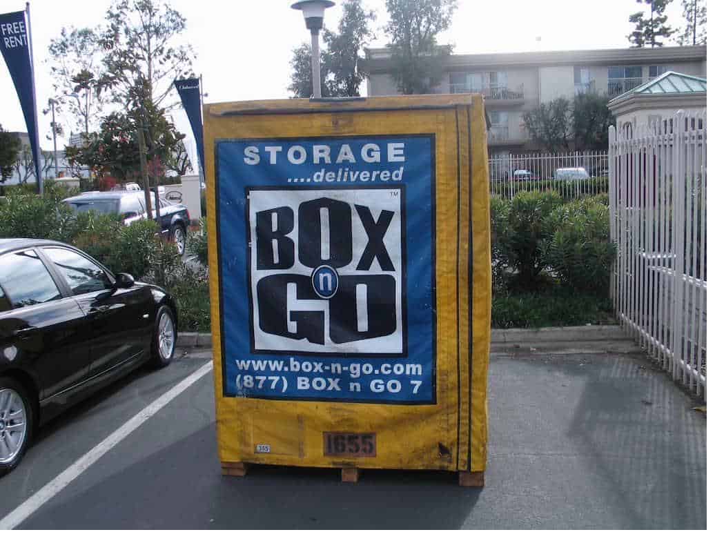Box-n-Go csuf summer storage container beside shrubs in a parking lot.