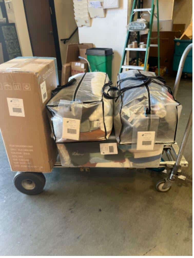 Student items including vacuum bags on a cart packed and labeled for Short-term storage for college students near Harvey Mudd.