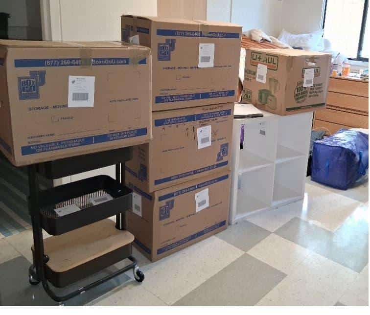 Student items including stacked moving boxes packed and labeled for storage for students.
