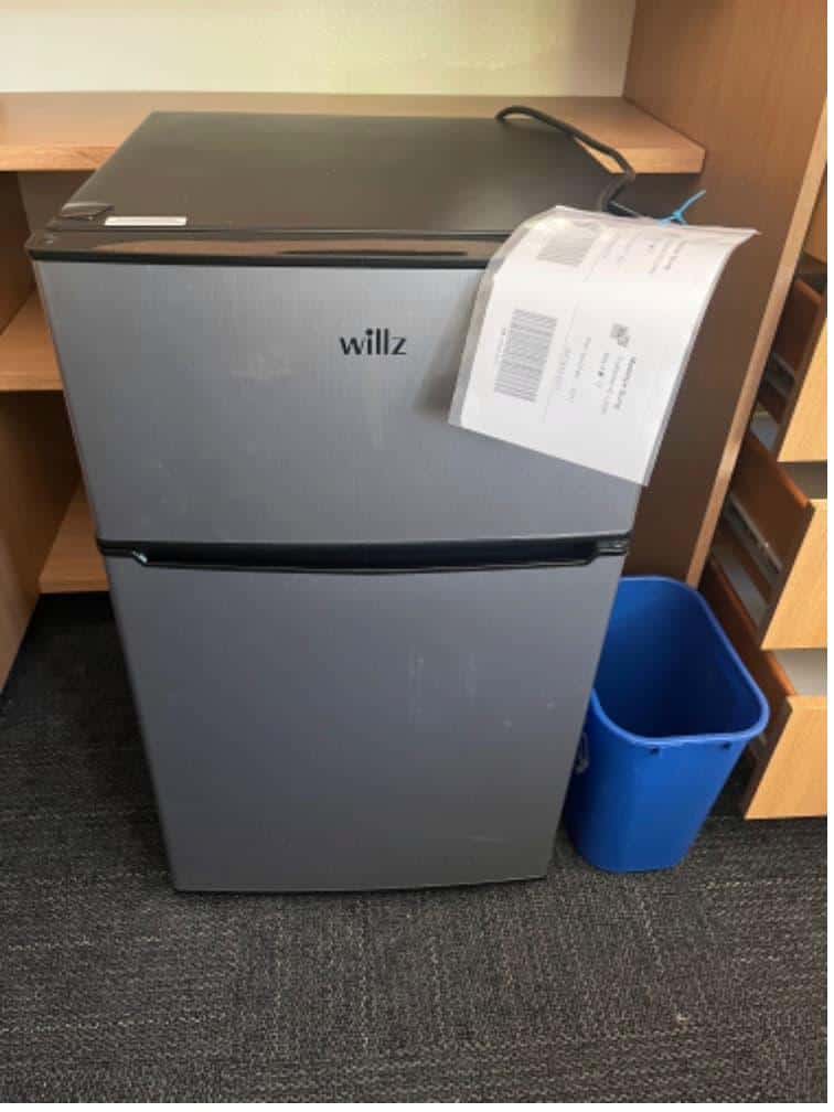 Student items including a gray mini fridge packed and labeled for storage near CMC.