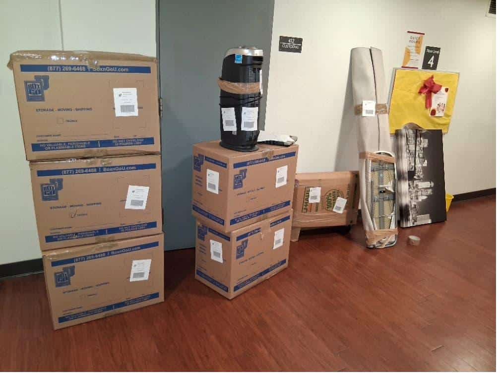 Student items including stacked boxes and a fan packed and labeled for ucla storage units.