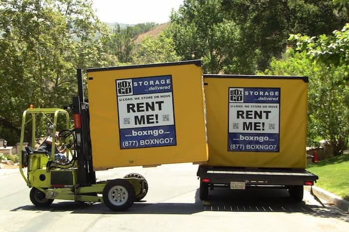 Box-n-Go truck-mounted forklift loading two Box-n-Go Flex storage containers at a residential delivery in Southern California