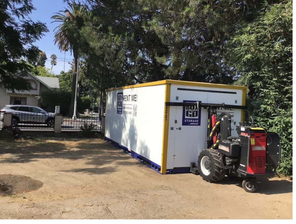 Box-n-Go XL storage container being placed by a walk-behind forklift unit at a residential property