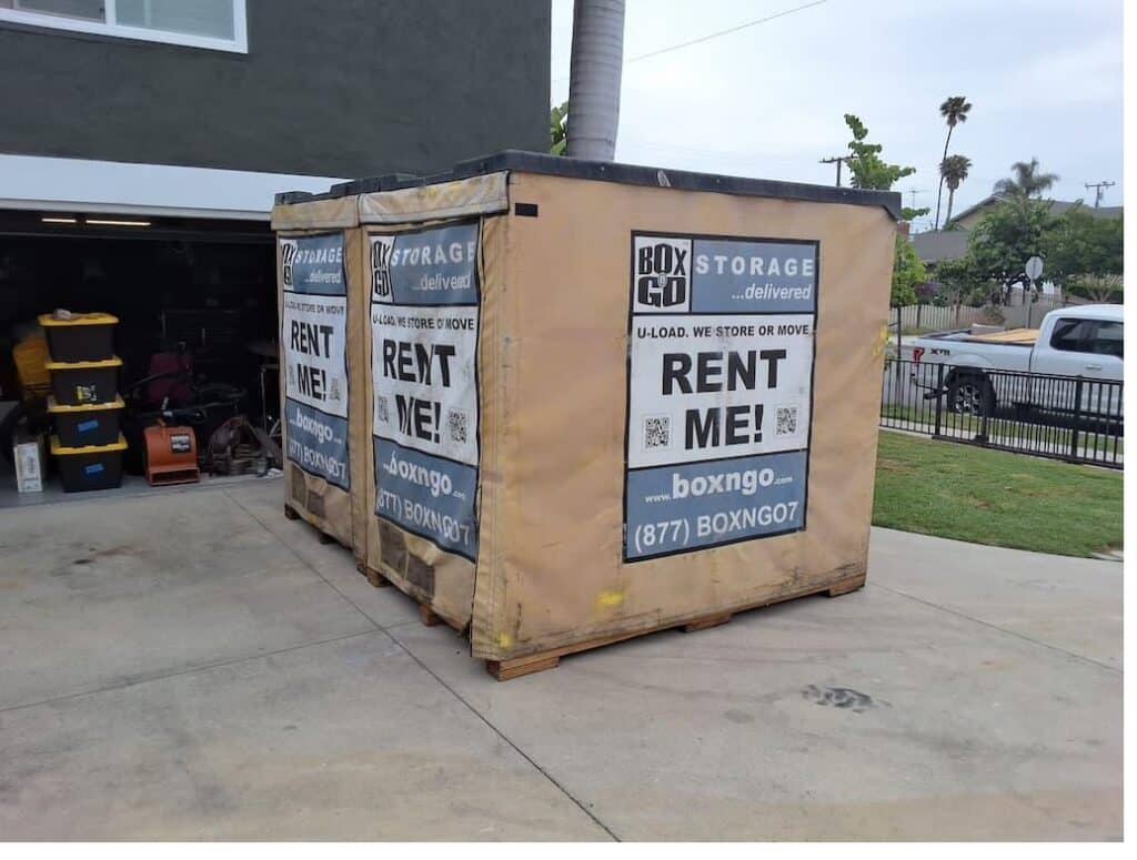 Two Box-n-Go Flex portable storage containers staged on a residential driveway in front of an open garage.