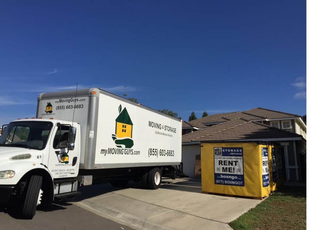 A move in progress at a home — a moving truck alongside Box-n-Go storage containers in the driveway.