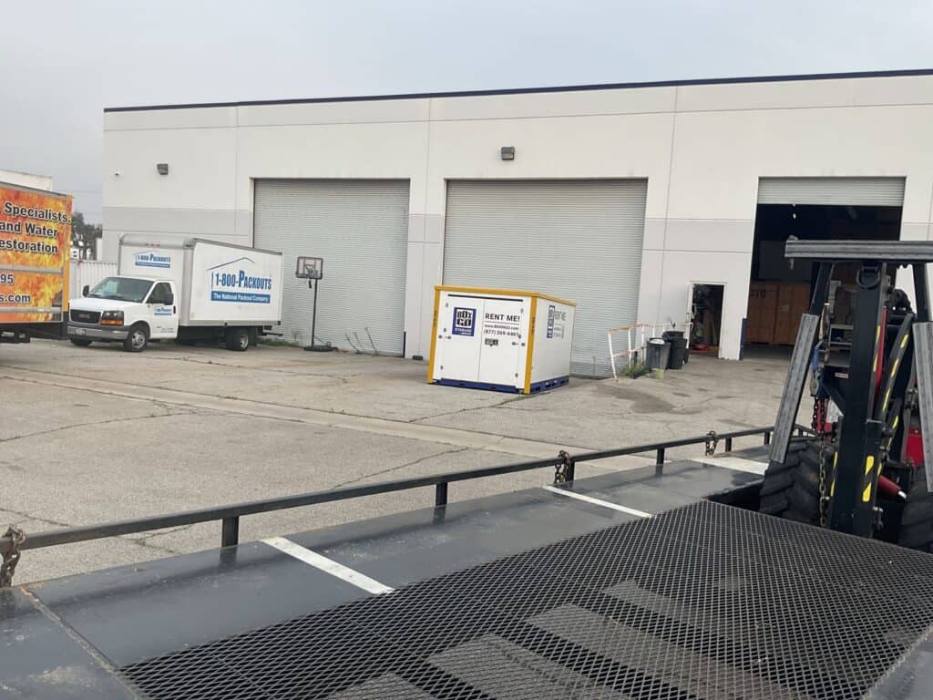 Box-n-Go truck-mounted forklift placing a jobsite storage container at an industrial site
