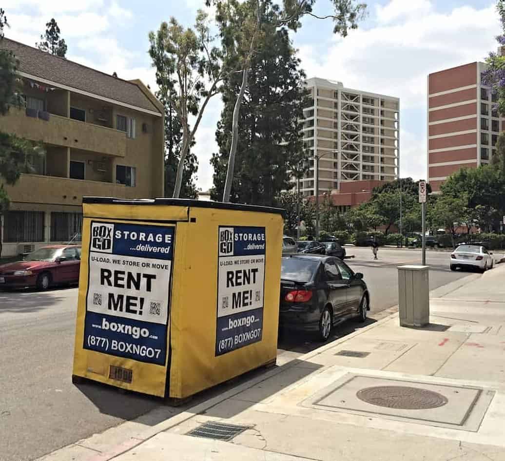 A Box-n-Go summer storage unit parked at the curb outside a student apartment building near campus.